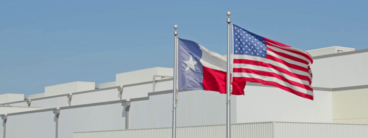Texas flag and American flag against blue sky and warehouse background in Burleson, TX at CORE X PREMIER