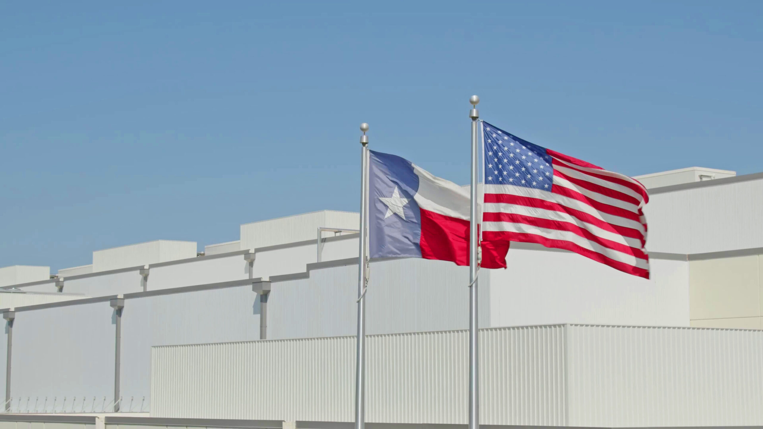 Texas flag and American flag against blue sky and warehouse background in Burleson, TX at CORE X PREMIER